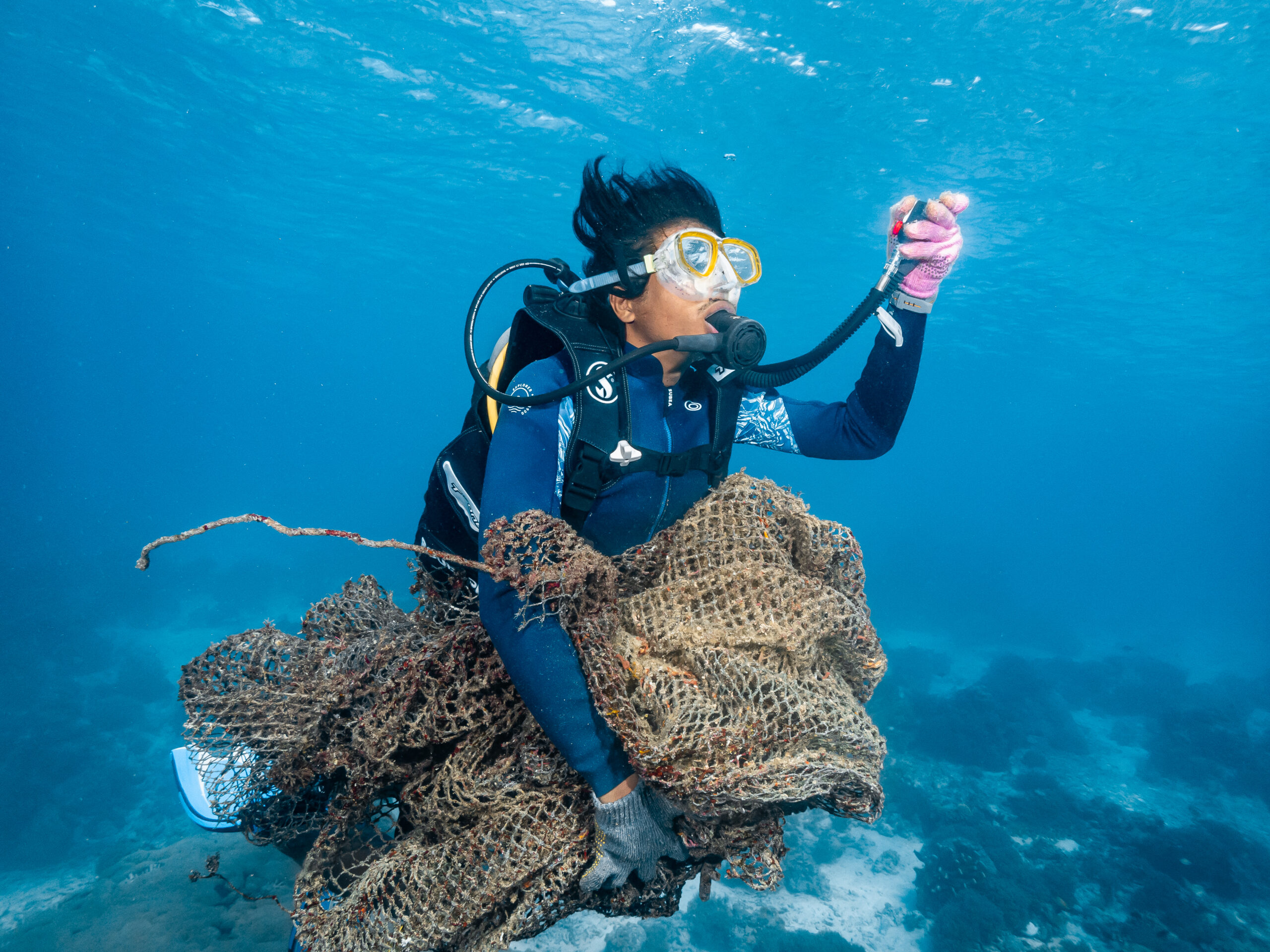 Coral gardener removing a ghost net from the ocean during a cleanup dive